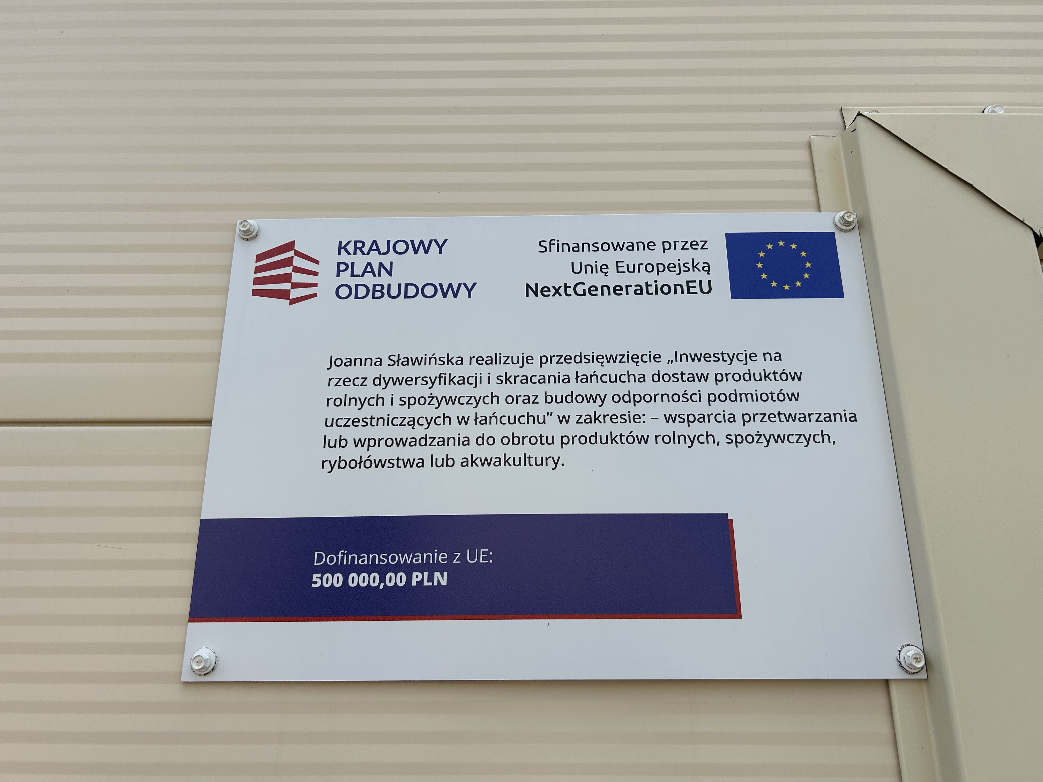 Tablica informacyjna projektu umieszczona na budynku hali produkcyjnej